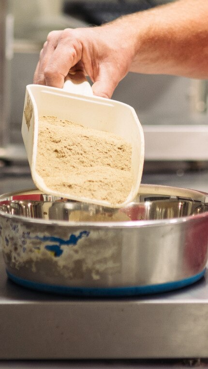 A Hill’s employee measuring ingredients on a scale