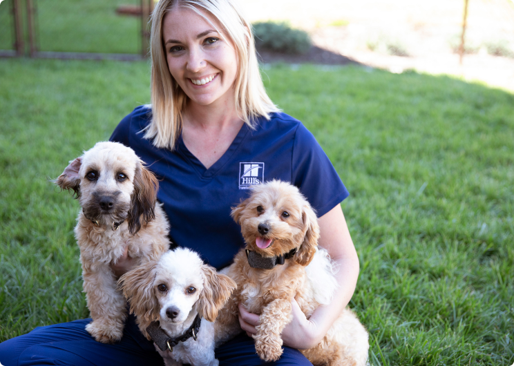 Hill's Pet служителл държащ три кученца в скута си