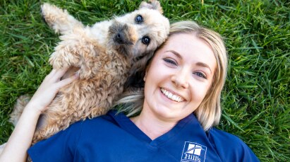 Hill's Pet служител, лежащ в тревата с куче